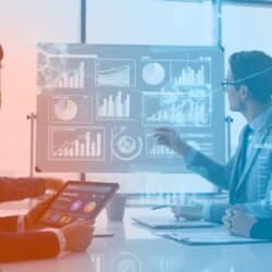 a group of people sitting at a table looking at a screen